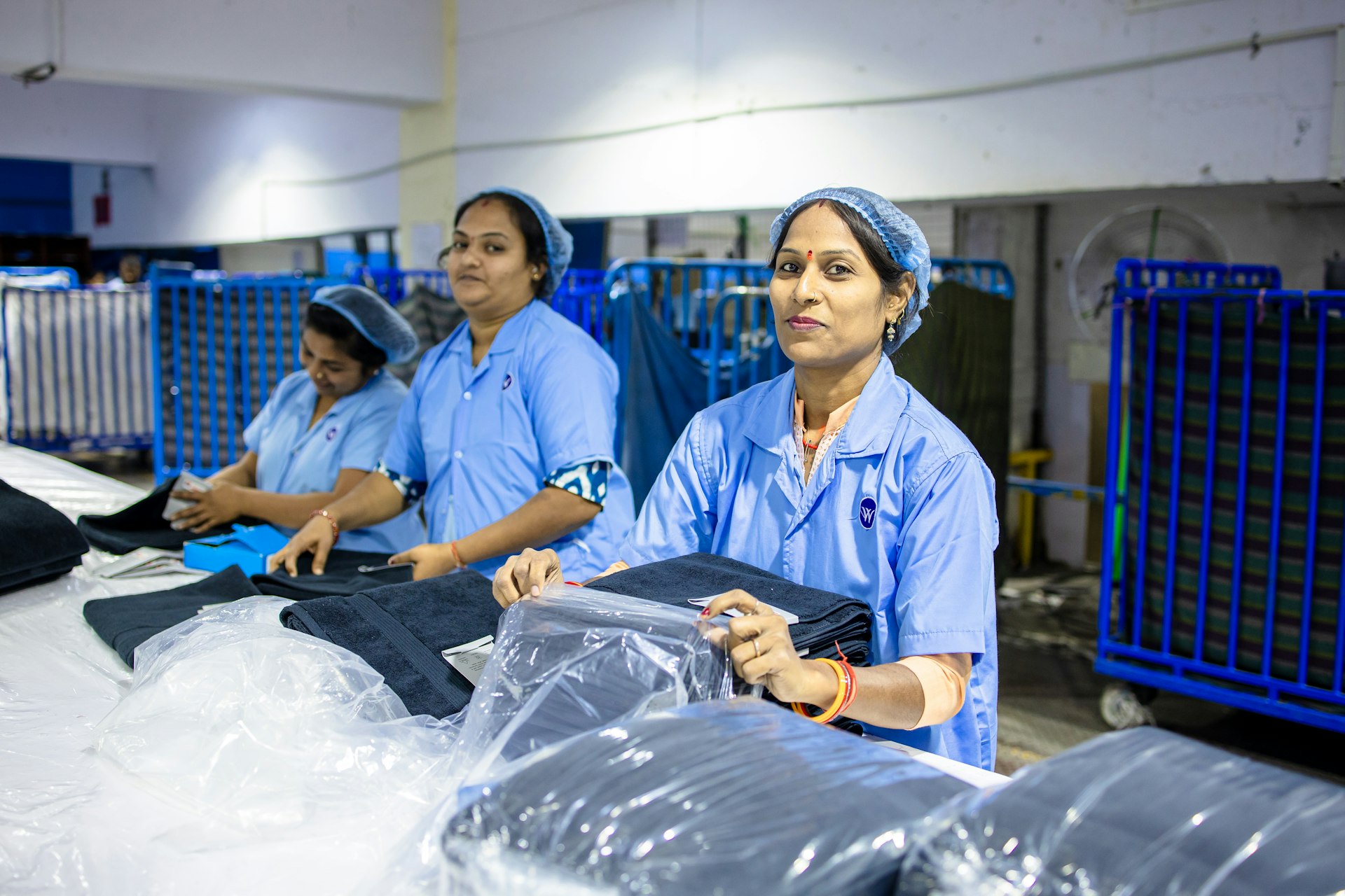 Workers prepare clothing in a factory setting.